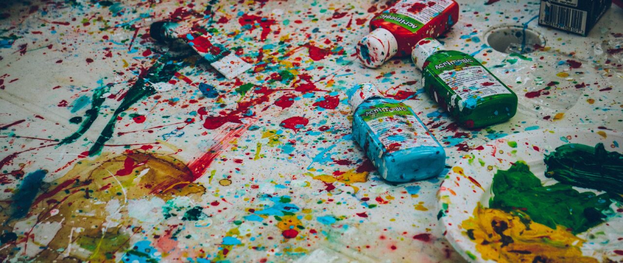 assorted-color bottles on white surface with paint scribbles
